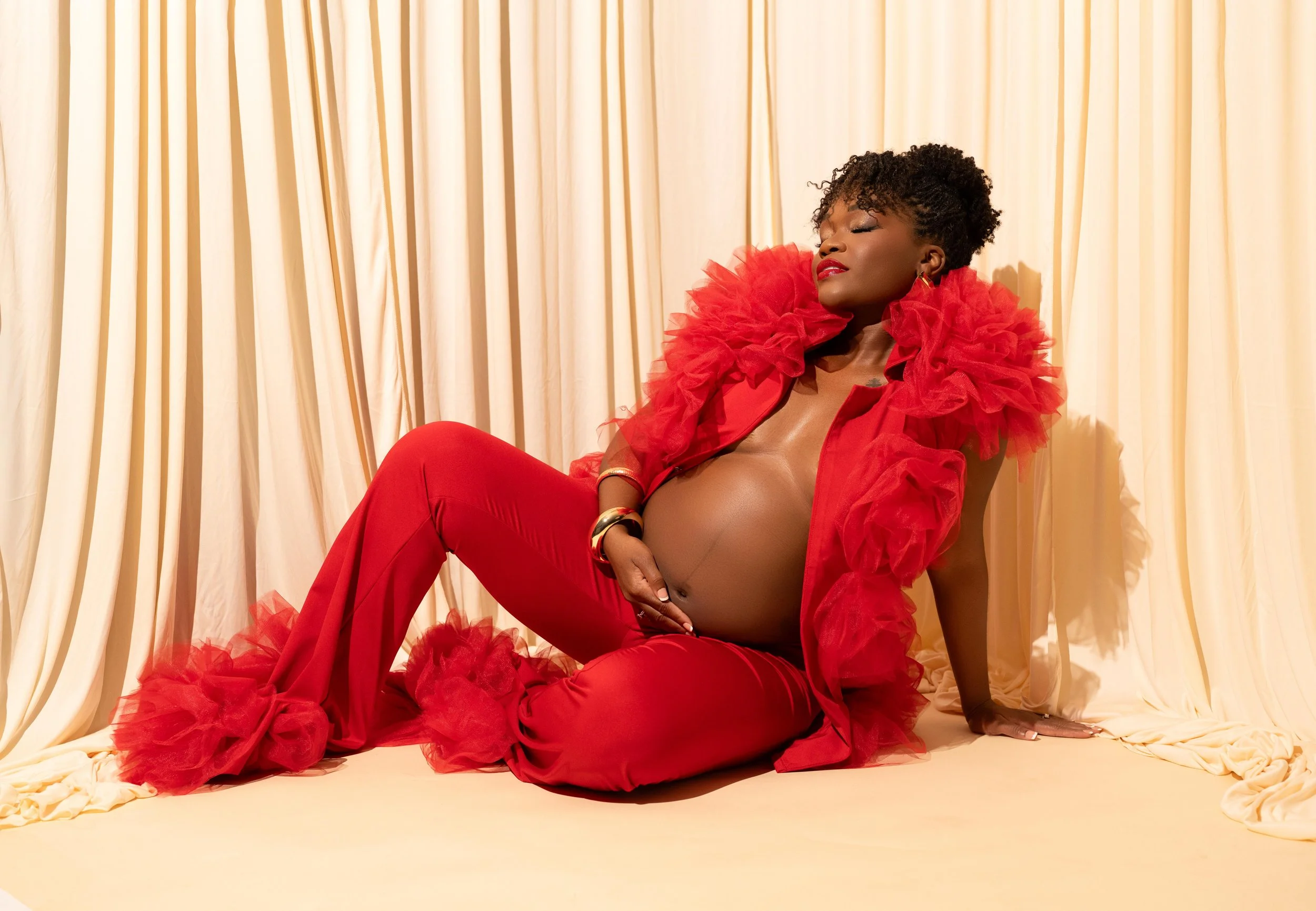 Bold editorial maternity portrait in a vibrant red look with dramatic studio styling, photographed in Dallas, Texas.
