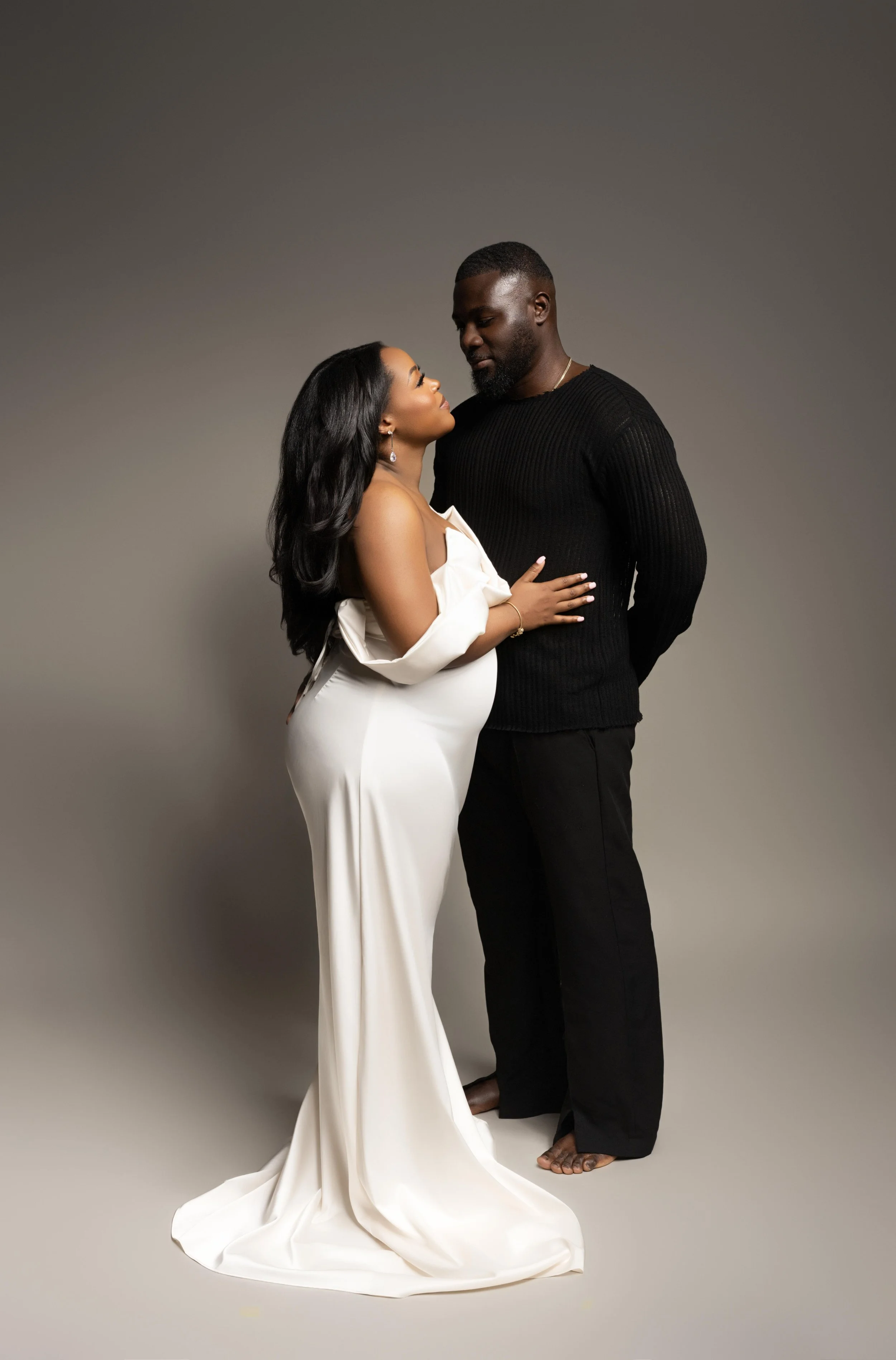 Elegant maternity portrait with partner in a classic studio setting, photographed in Plano, Texas.