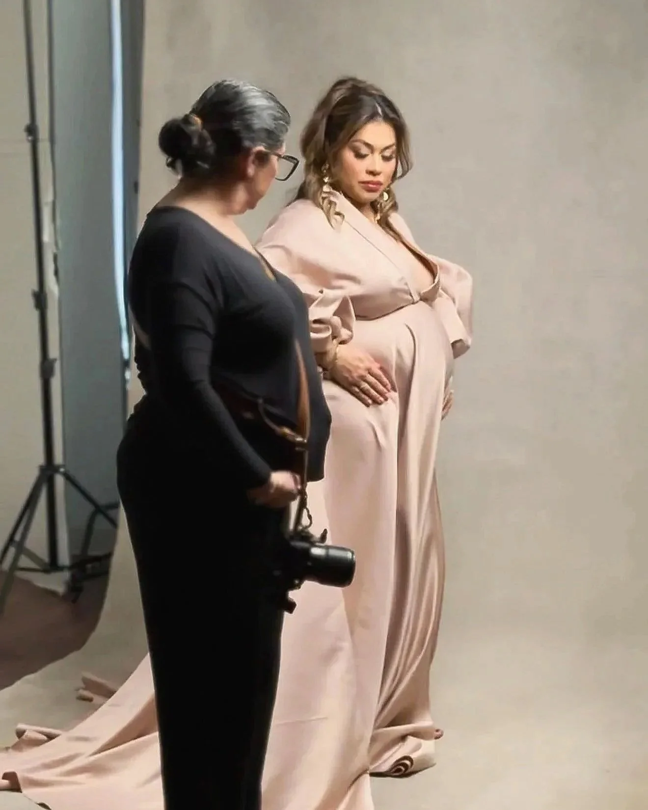 Maternity photographer providing posing guidance to a pregnant client during her Dallas studio session.