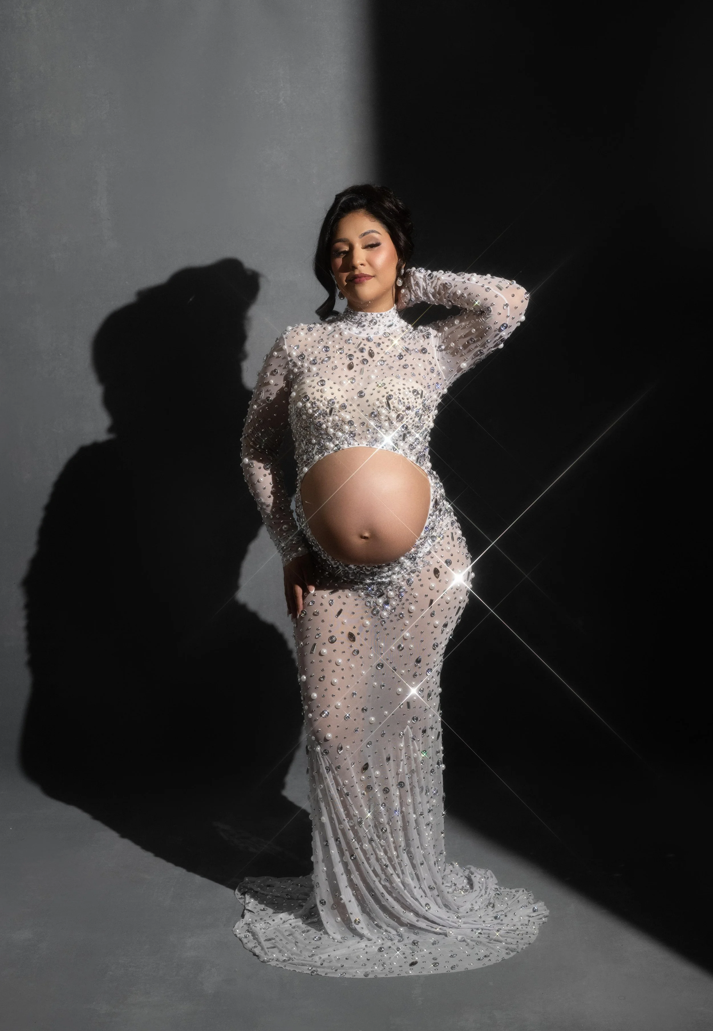 Luxury maternity portrait in Dallas featuring a sparkling crystal gown with dramatic studio lighting.