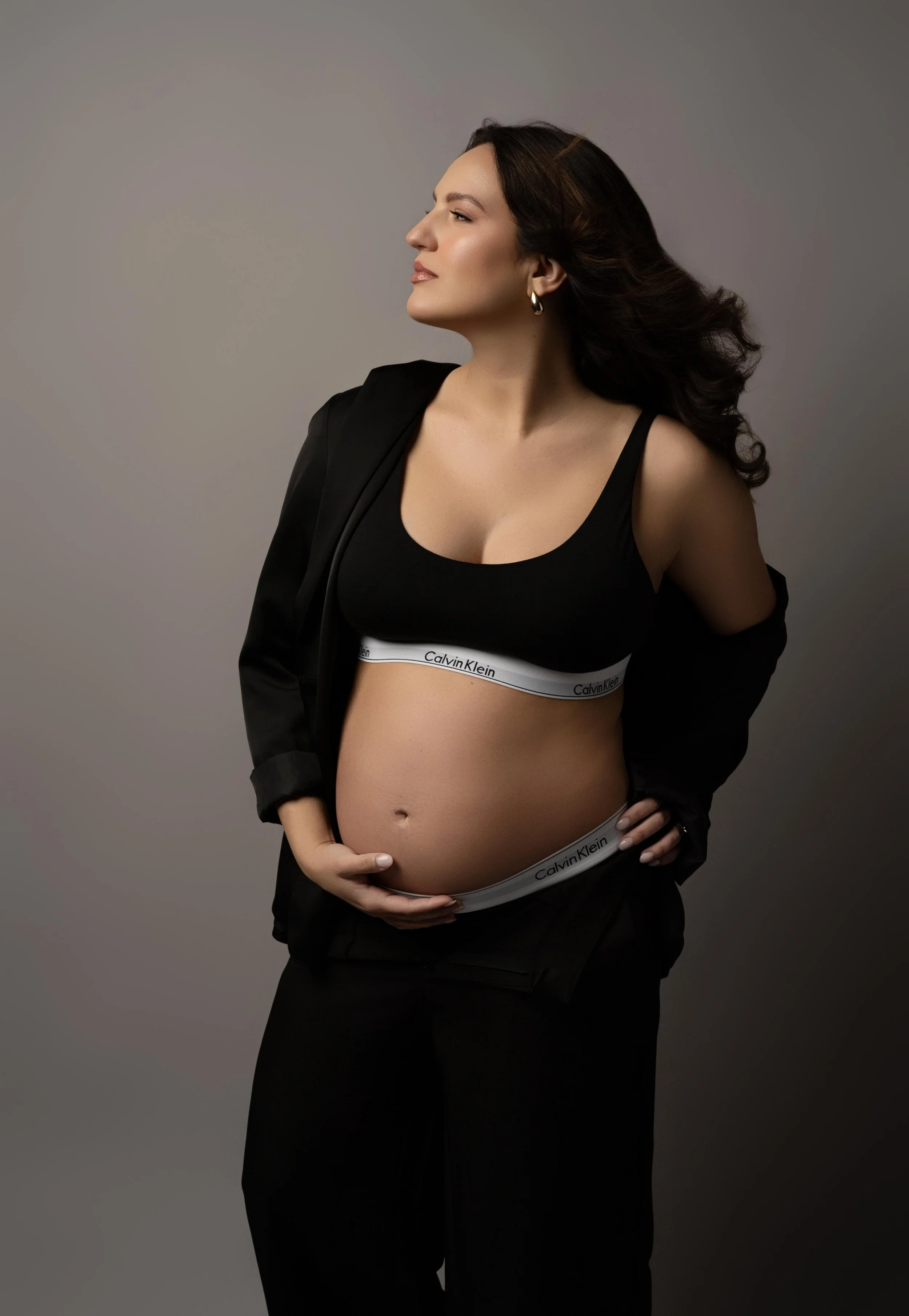 Modern studio maternity portrait in a black two-piece look with elegant styling, photographed in Carrollton, Texas.