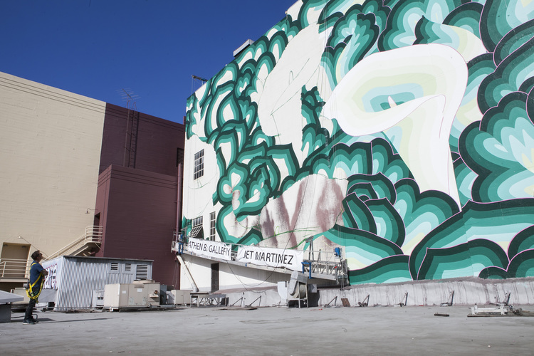 Image of Jet Martinez in 2016 when working on his downtown Oakland mural, ““ There’s More to Green than Money.” Source: Amadeus Magazine