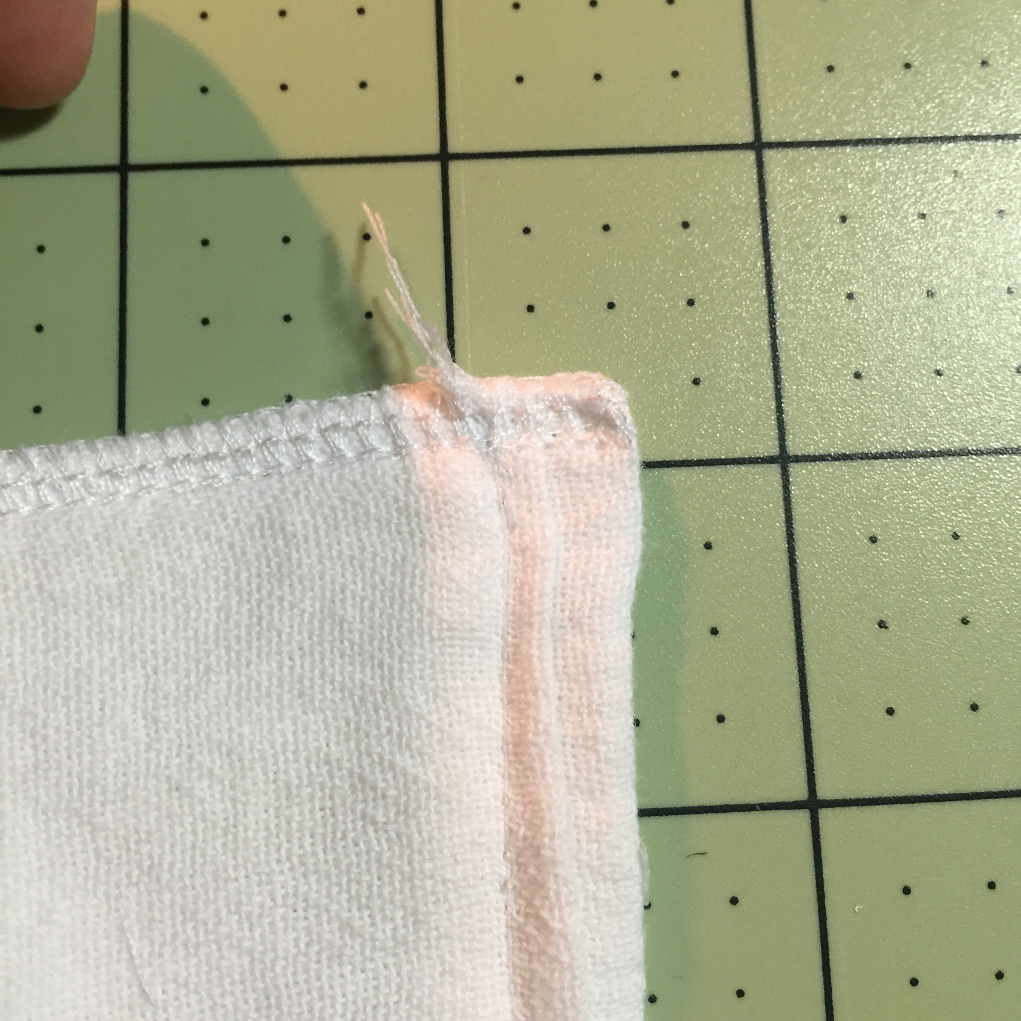 Once you pull through, the tail will be caught and safe in the serged stitches. Cut the extra tail.