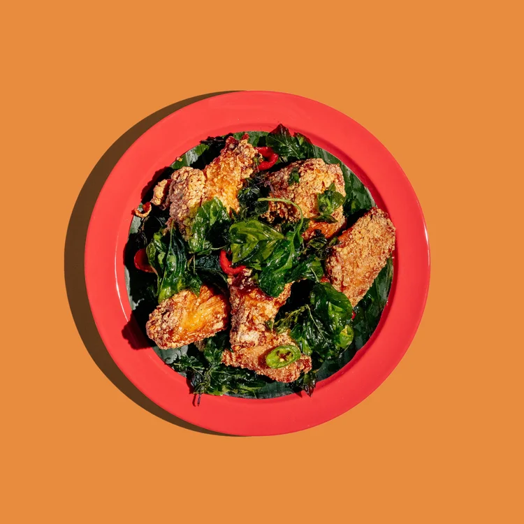 Fried chicken wings with herbs and sliced green chilli