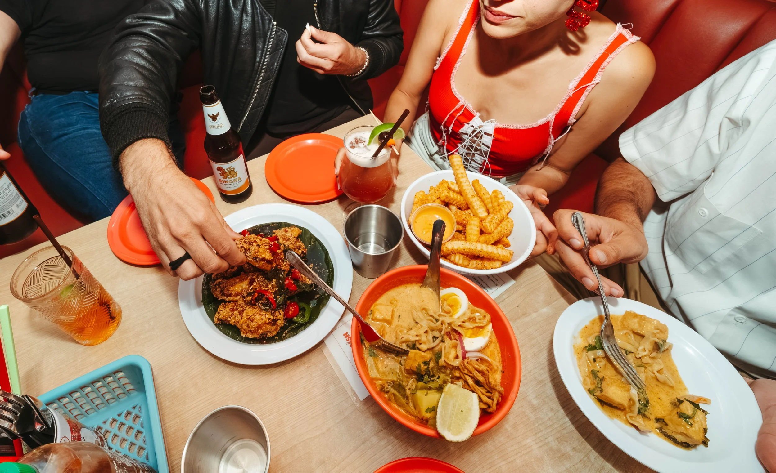 People enjoying a meal at a table with various Asian dishes, drinks, and condiments.