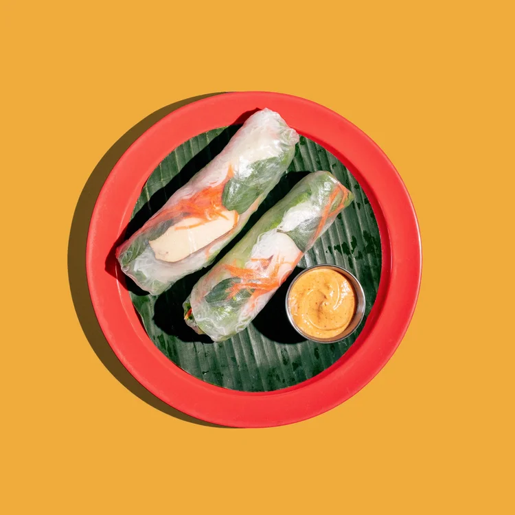 Fresh summer rolls on a banana leaf with peanut dipping sauce
