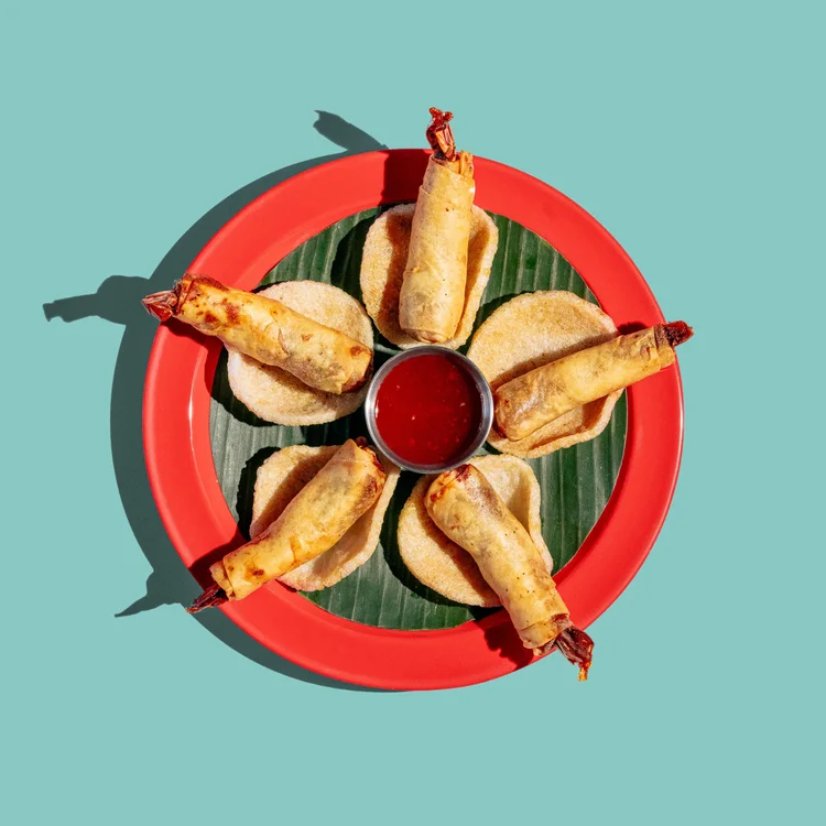 Crispy shrimp rolls arranged around a bowl of sweet chili sauce