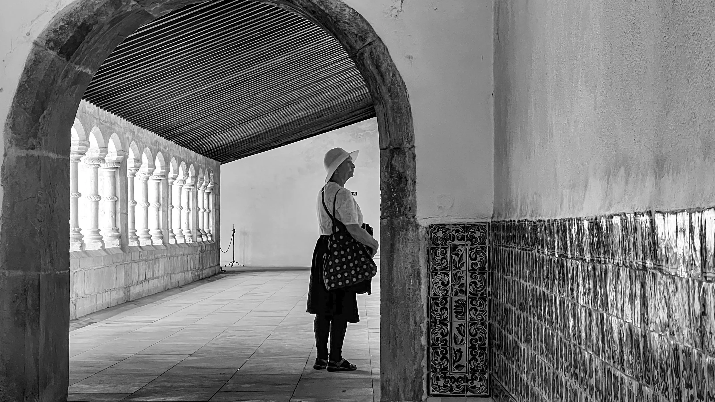 Leslie in Coimbra. Leslie standing just past an arch looking to the right. In an old monastery.