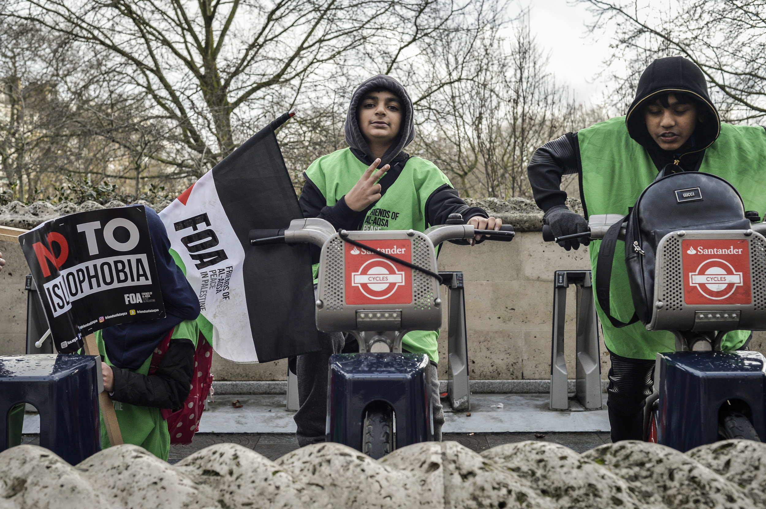 A boy shows the peace sign whilst playing on a Santander bike after the protest.