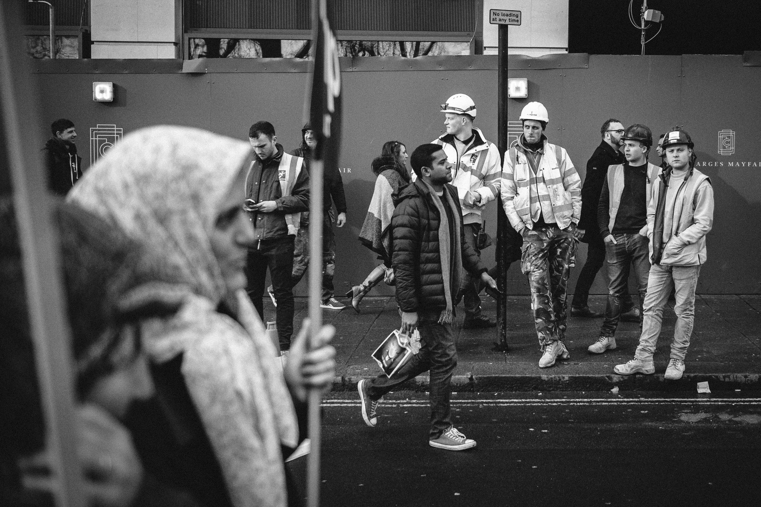 Construction workers watch as the protest passes through Piccadilly. 