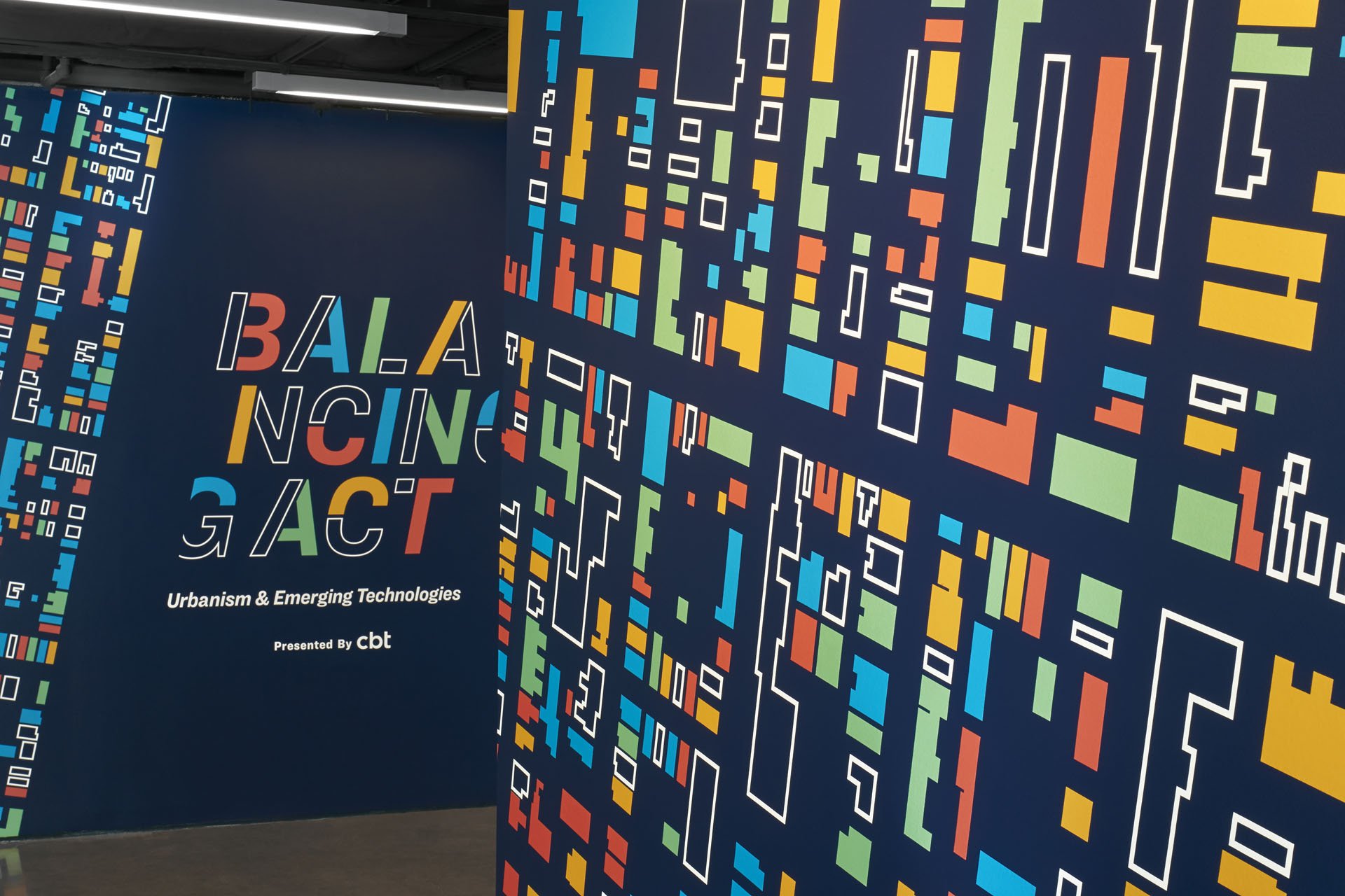 A photo of the exhibits entry walls adorned with colorful blocks forming an abstract geometric pattern resembling buildings in a city block