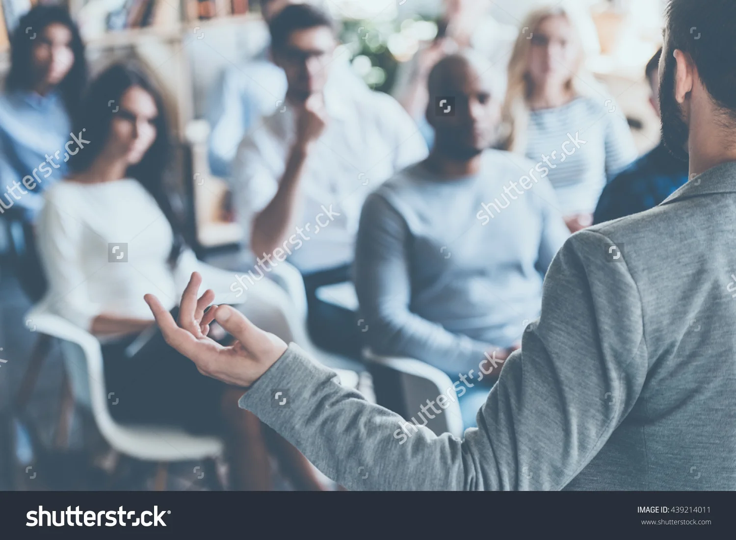 stock-photo-business-coach-rear-view-of-man-gesturing-with-hand-while-standing-against-defocused-group-of-439214011.jpg