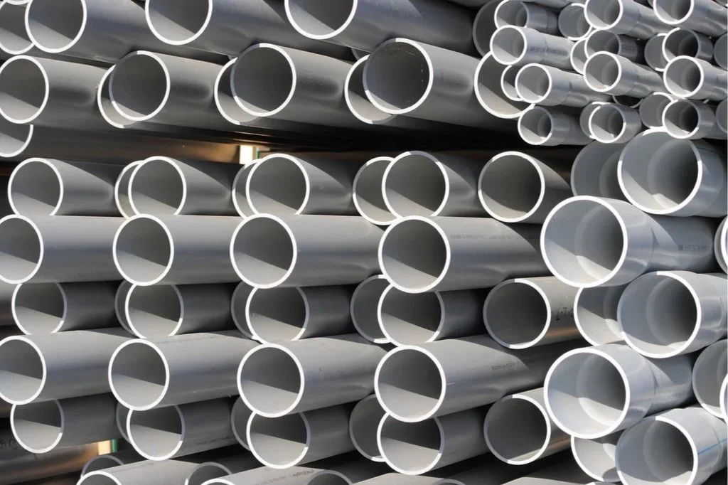Stacked white PVC pipes arranged on a rack.