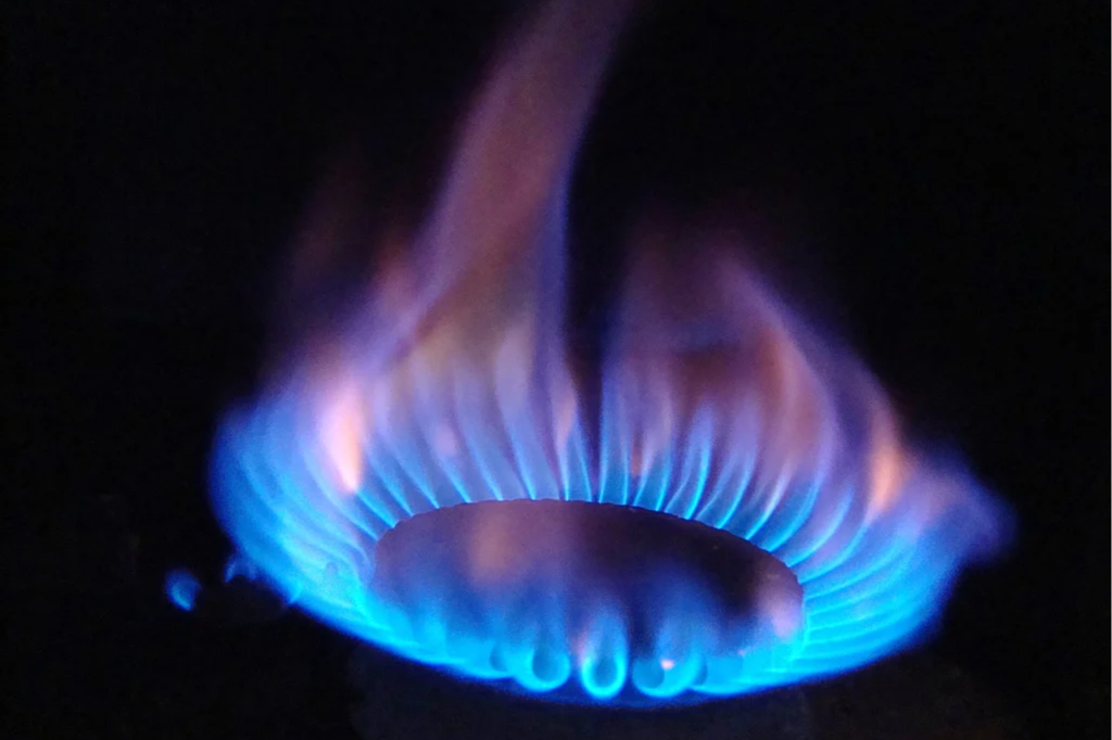 Close-up of a blue and orange gas flame on a stove burner.