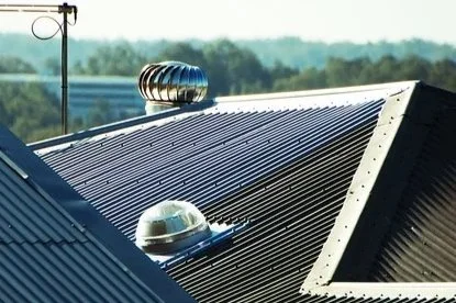 Close-up of a solar panel on a rooftop with a wind turbine and dome-shaped security camera.