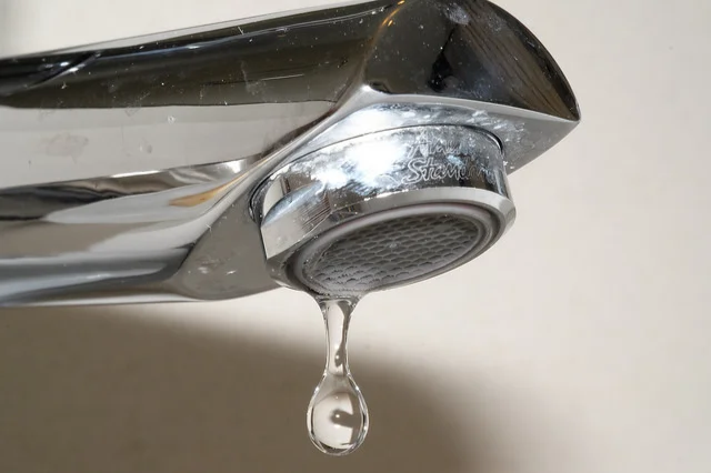 Close-up of a dripping faucet with water falling from it.