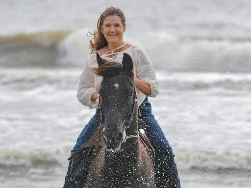 Denise Raymond, Senior Account Manager at Expert Bookers, riding her horse outdoors.