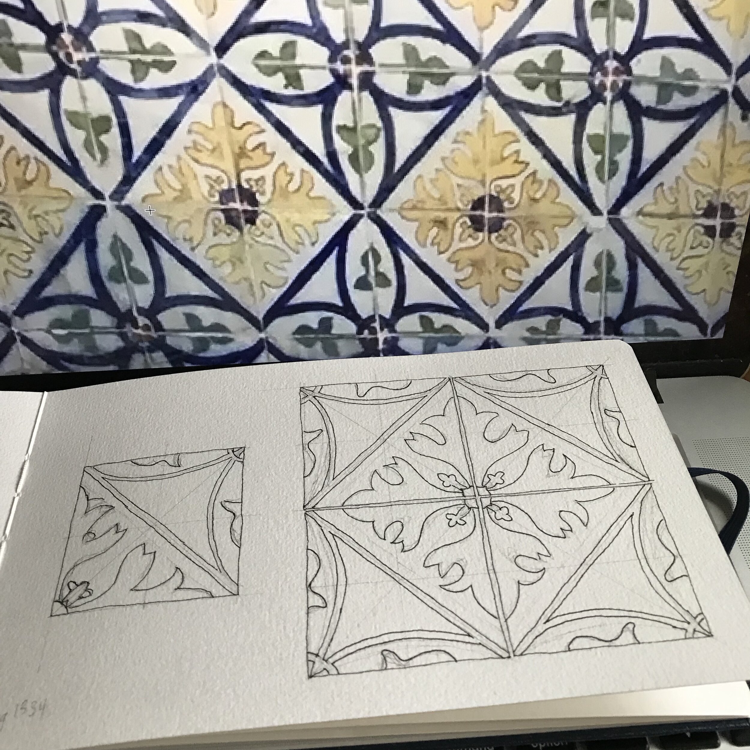 Pattern in sketchbook with enlarged photo reference of tiles in the background