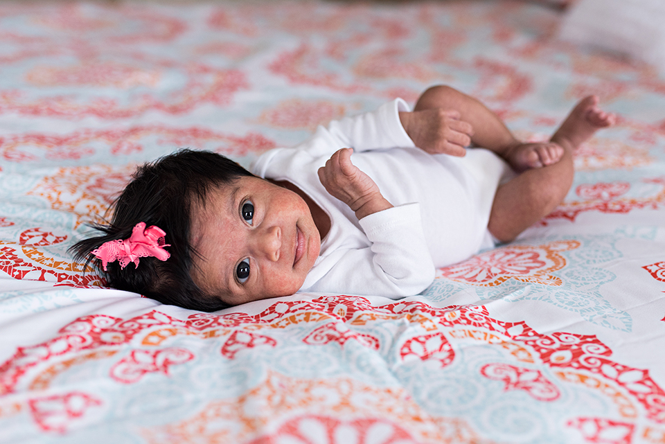 newborn girl with pink bow laying in bed southington, connecticut newborn photographer