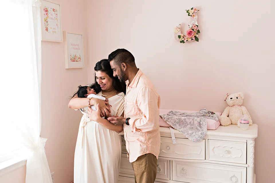 mom and day holding newborn daughter in nursey southington connecticut newborn photographer