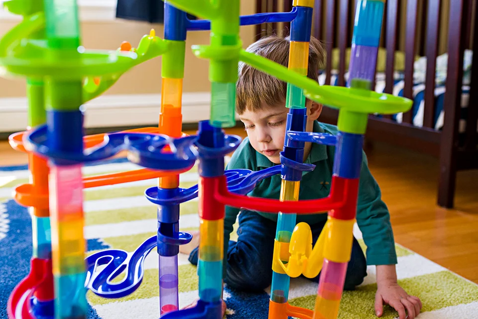 boy playing with marble run in bedroom on green carpet west hartford connecticut family documentary photography