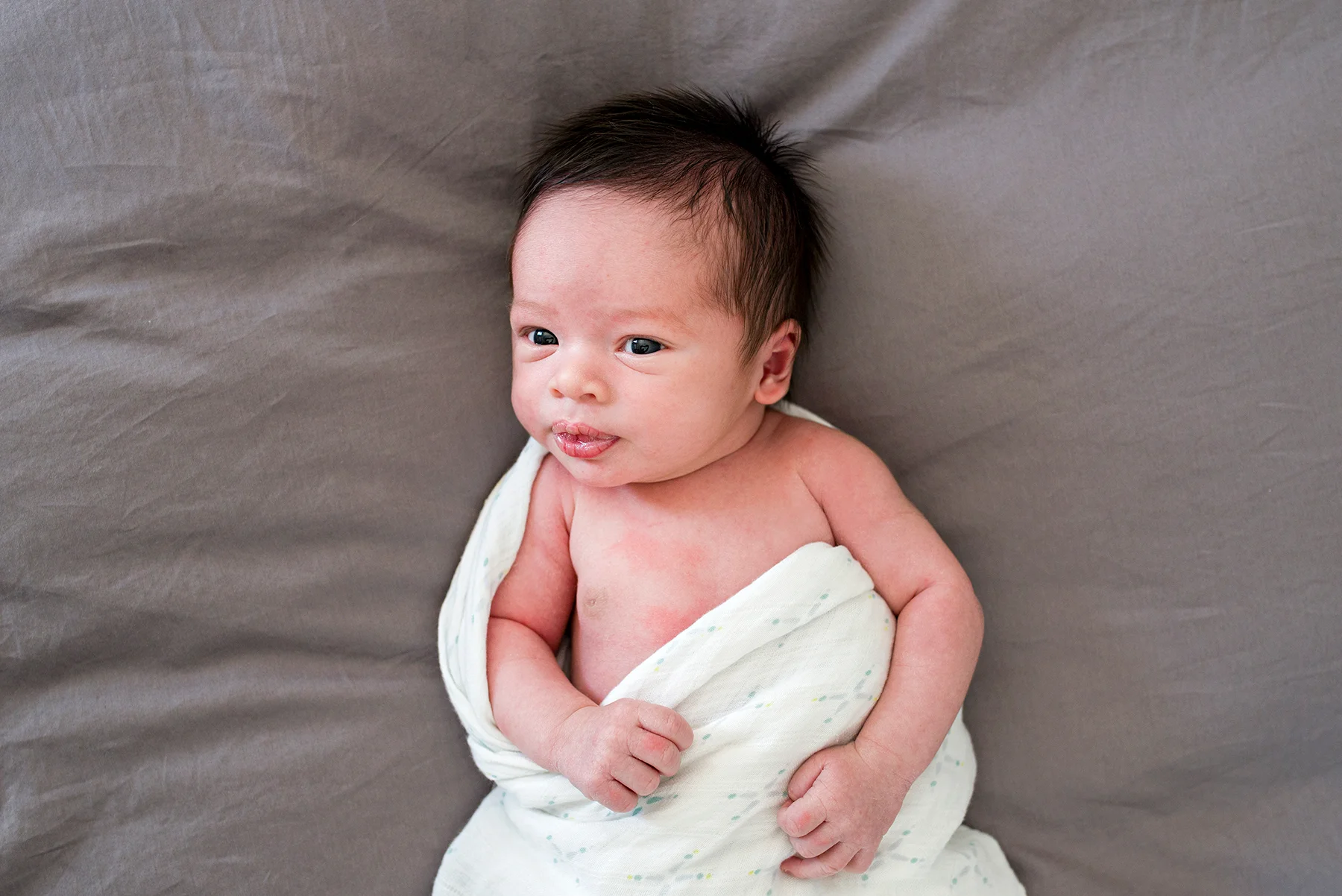 newborn baby boy laying on mom and dads bed at lifestyle newborn photography middletown connecticut