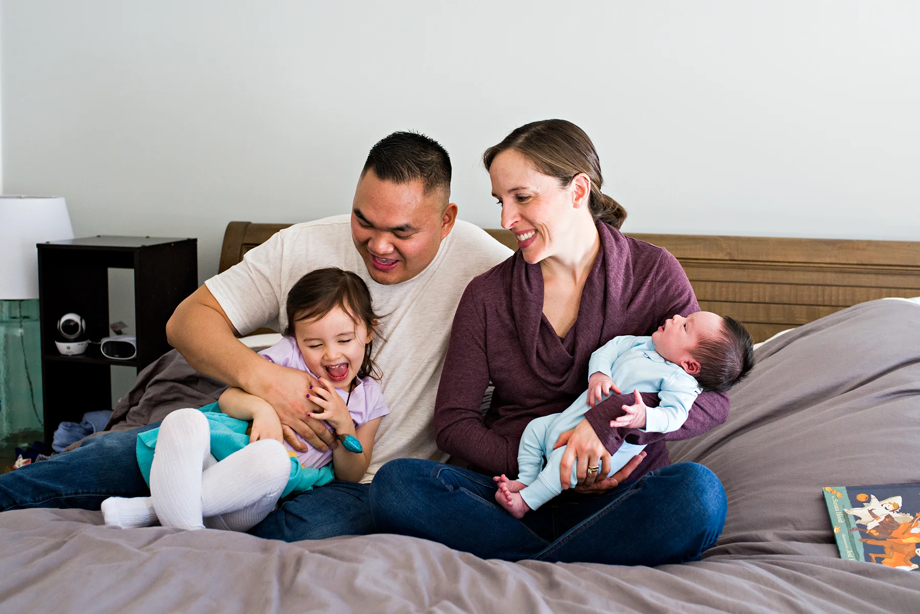 dad tickling daughter on bed at lifestyle newborn photography middletown connecitcut