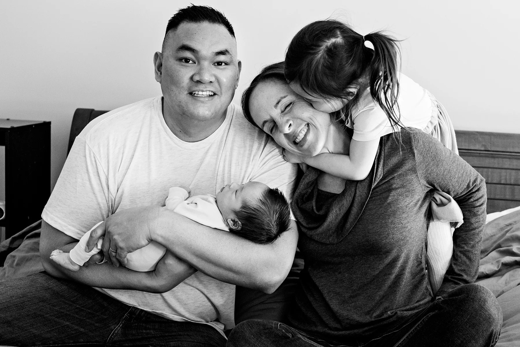 dad holding baby boy while daughter kisses mom lifestyle newborn photography session