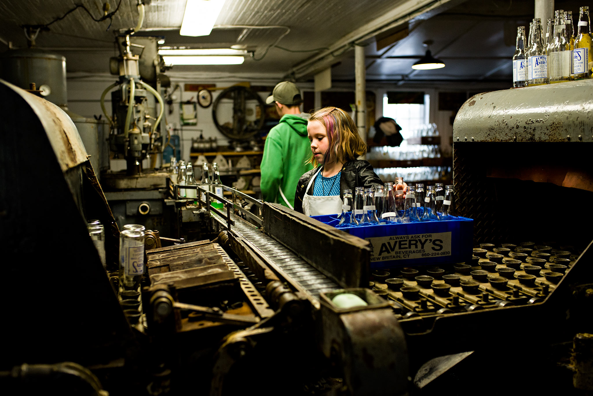 girl placing soda bottles on machine to be filled averys soda connecticut documentary photography
