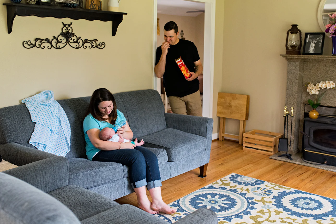 mom feeding newborn bottle while dad has a snack southington ct newborn photography