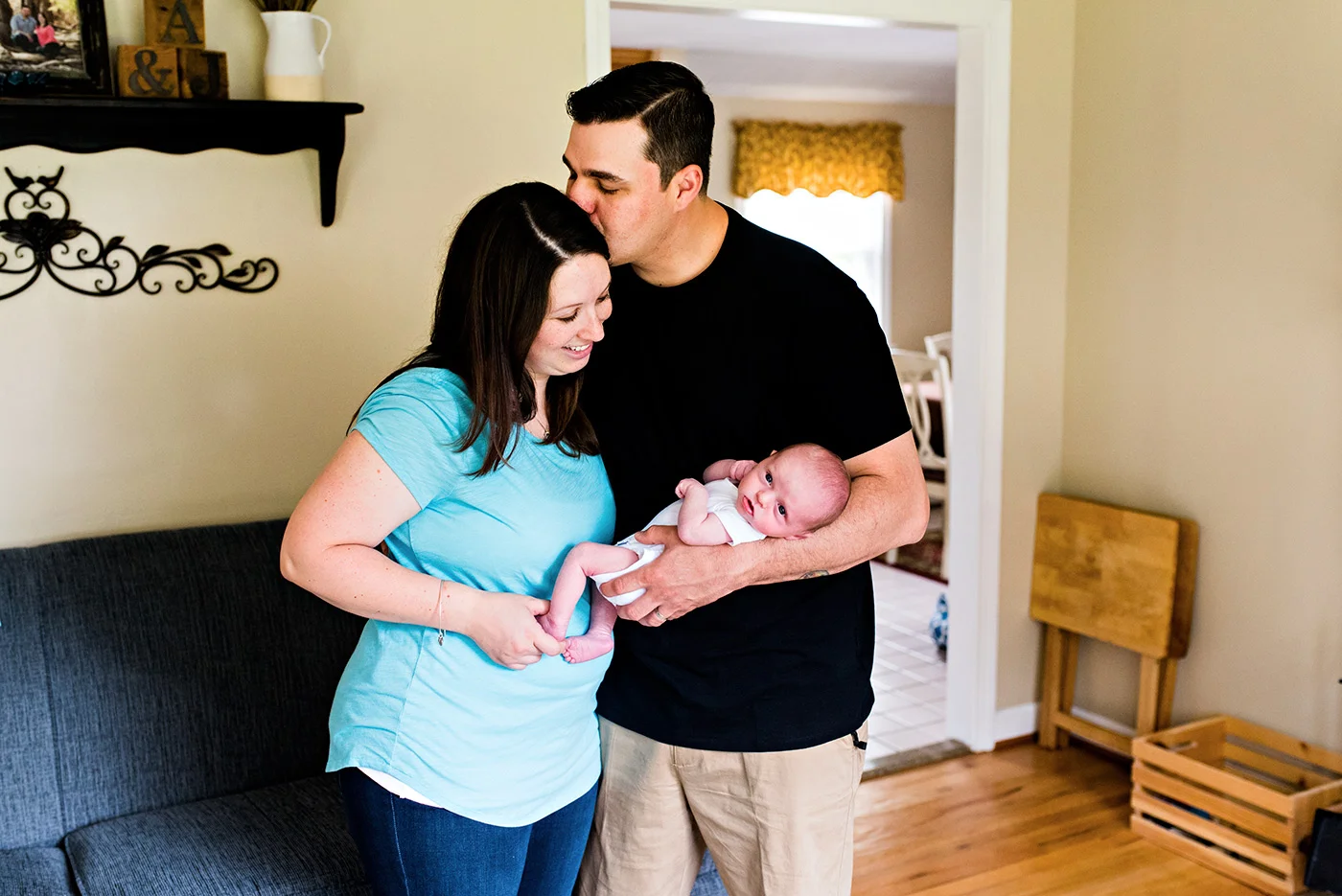 husband kissing wife while holding baby southington ct newborn photography