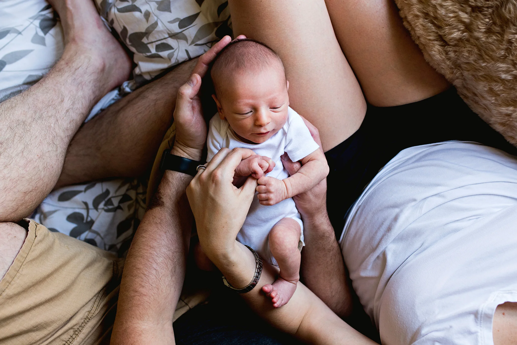 newborn on mom and dad's lap during ct newborn photography session in manchester, ct
