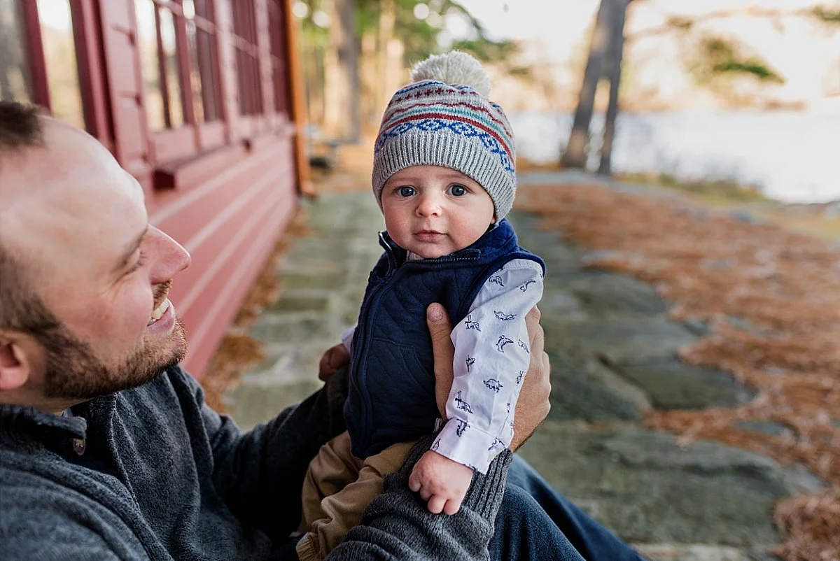Infant boy in snow hat sitting outside during Connecticut family photography session.