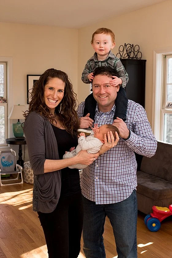 family posing for newborn photograph in their home.