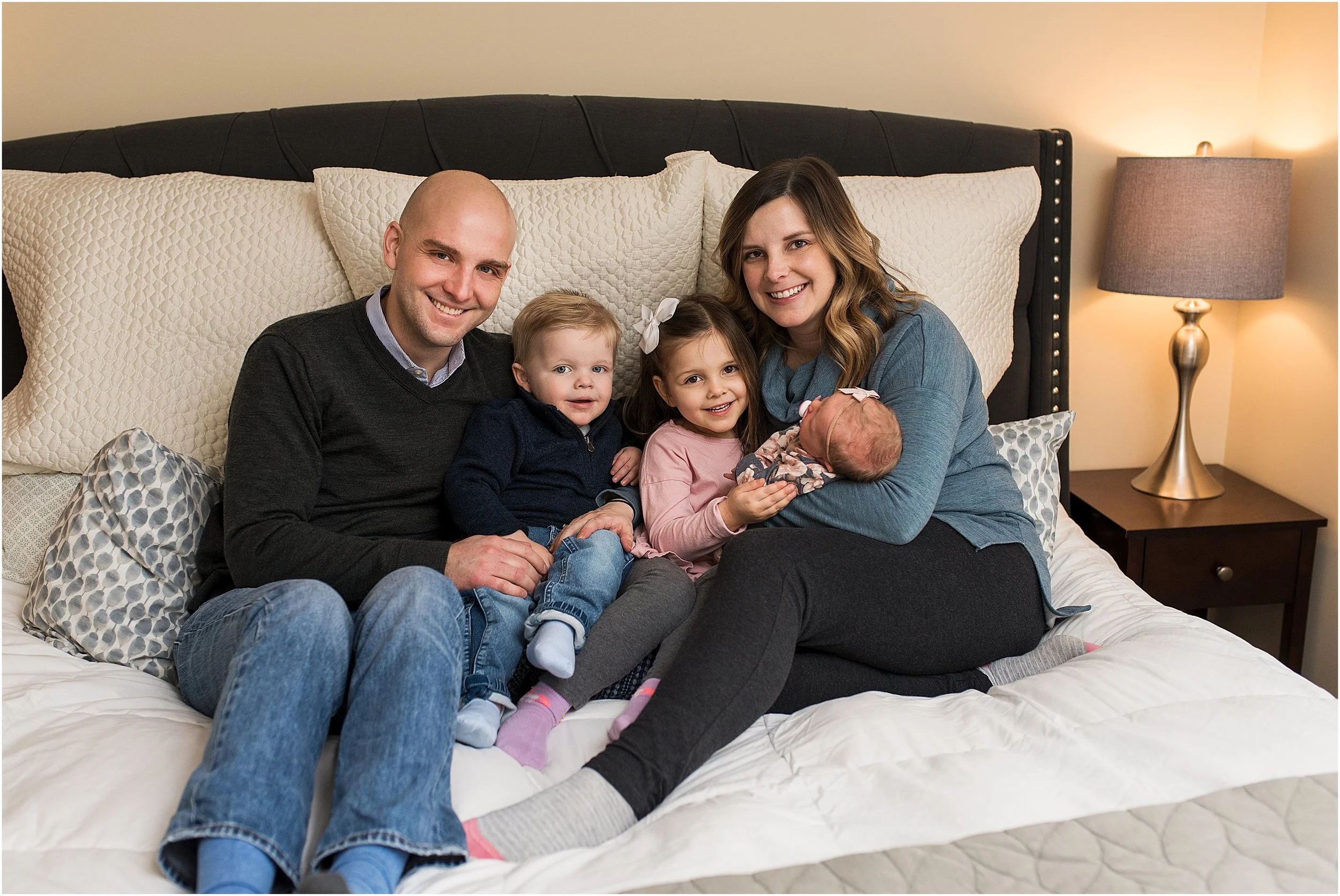 Mom and dad snuggling with children during an at home baby photography session in New Haven, CT