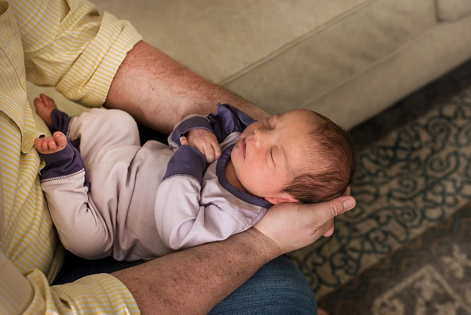 Baby laying in Dad’s arms while wearing a purple outfit during her CT newborn photography session