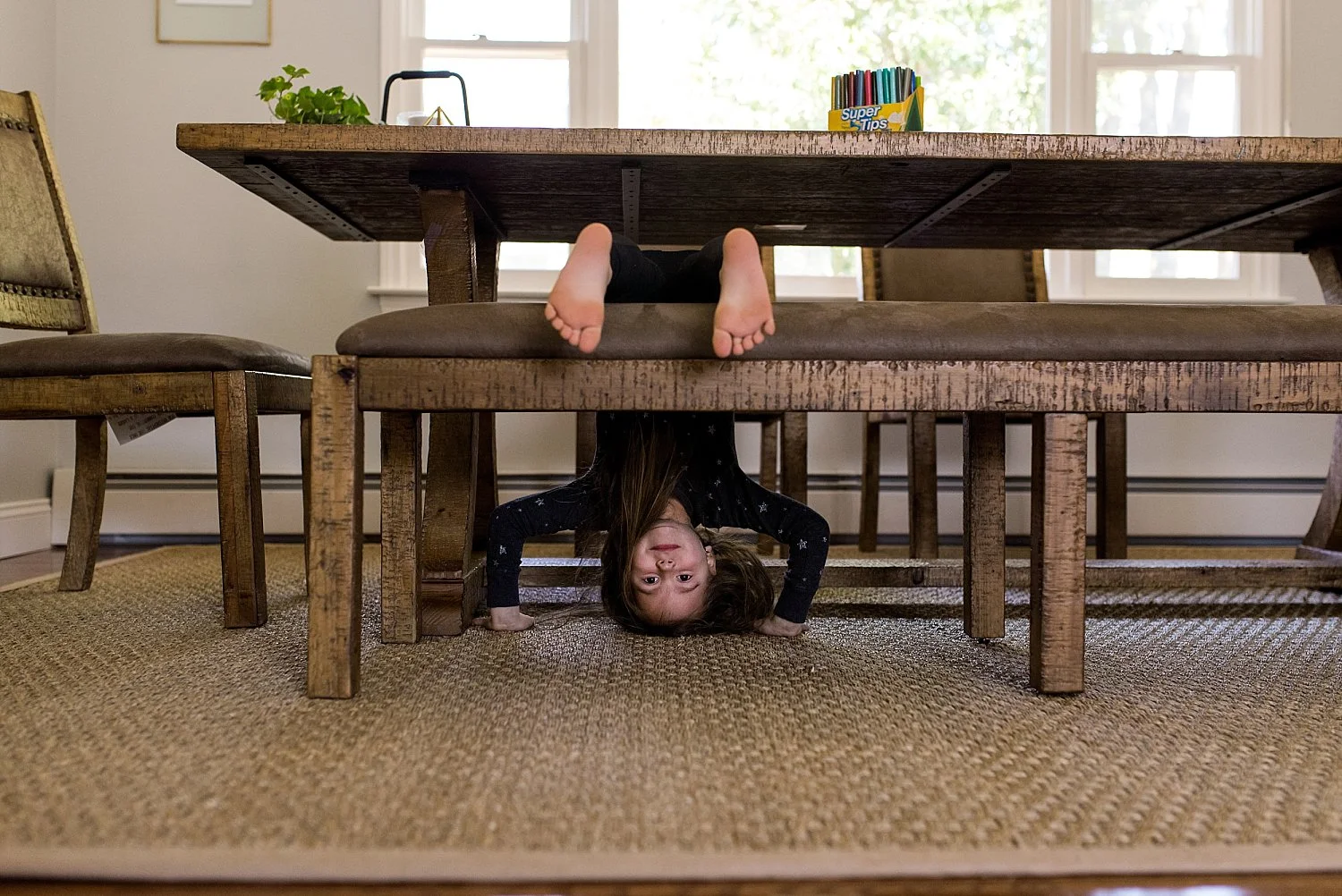 girl hanging upside down on dinning room table at her South Windsor CT family photo session