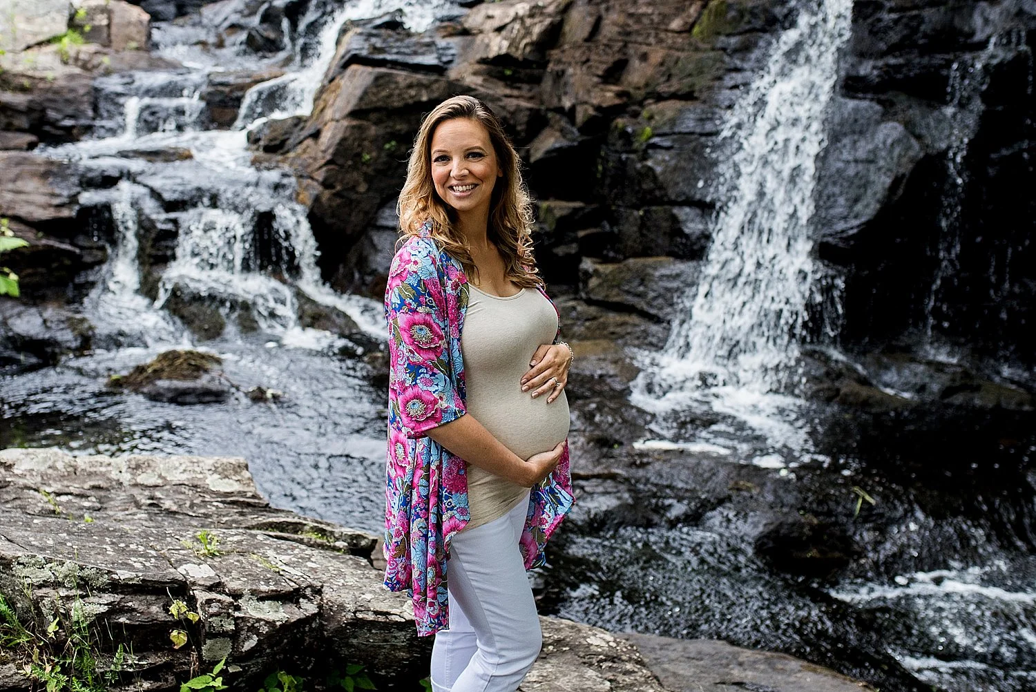 expecting mom in floral kimono in front of waterfall during her Connecticut maternity photography session
