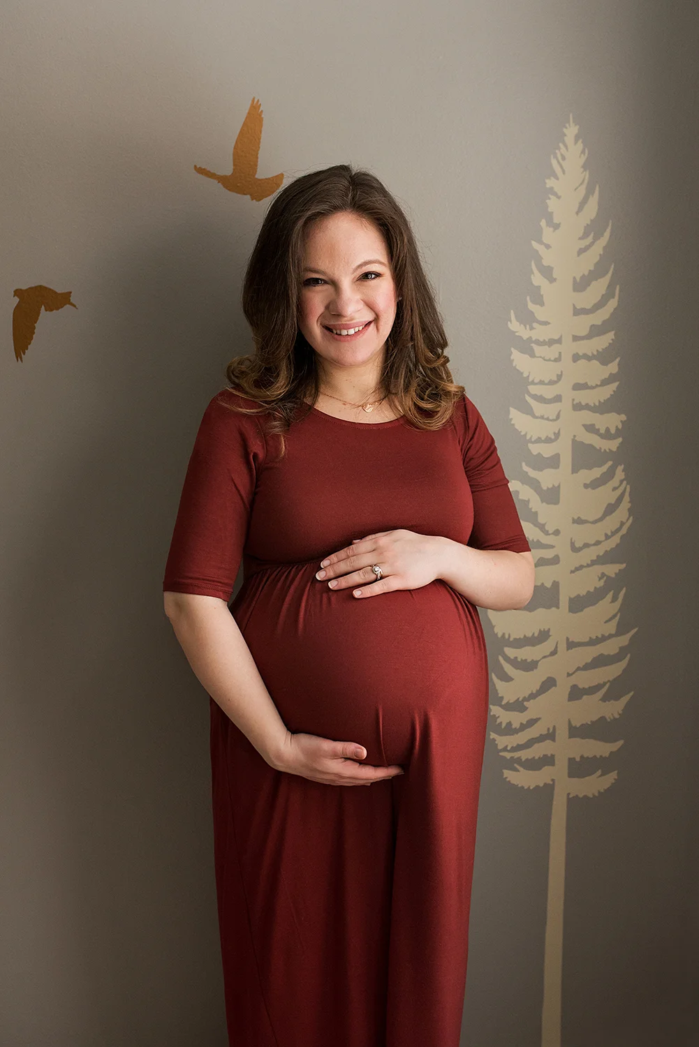 Maternity photographer CT. Pregnant mom in red dress in her baby’s nursery