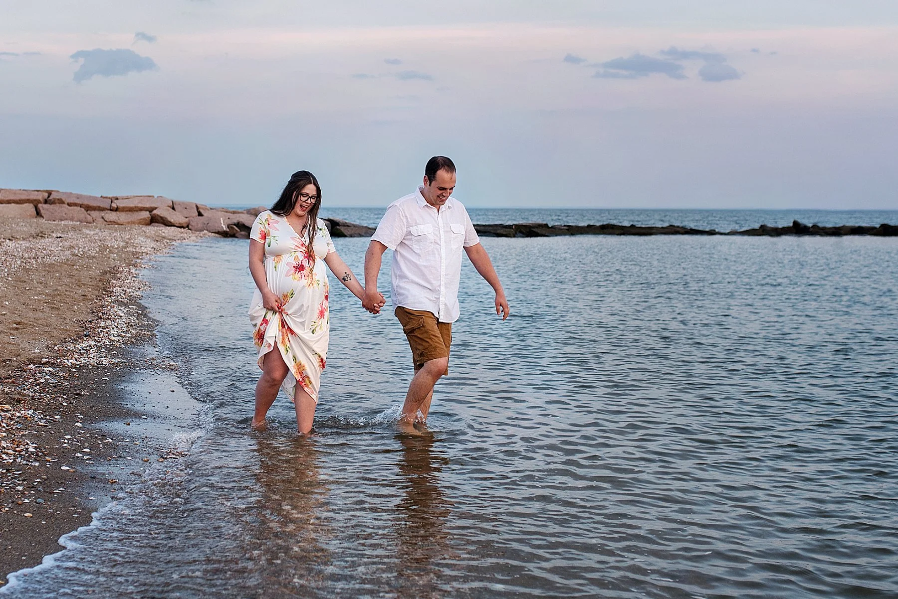 husband and wife laughing and holding hands during connecticut maternity photography session