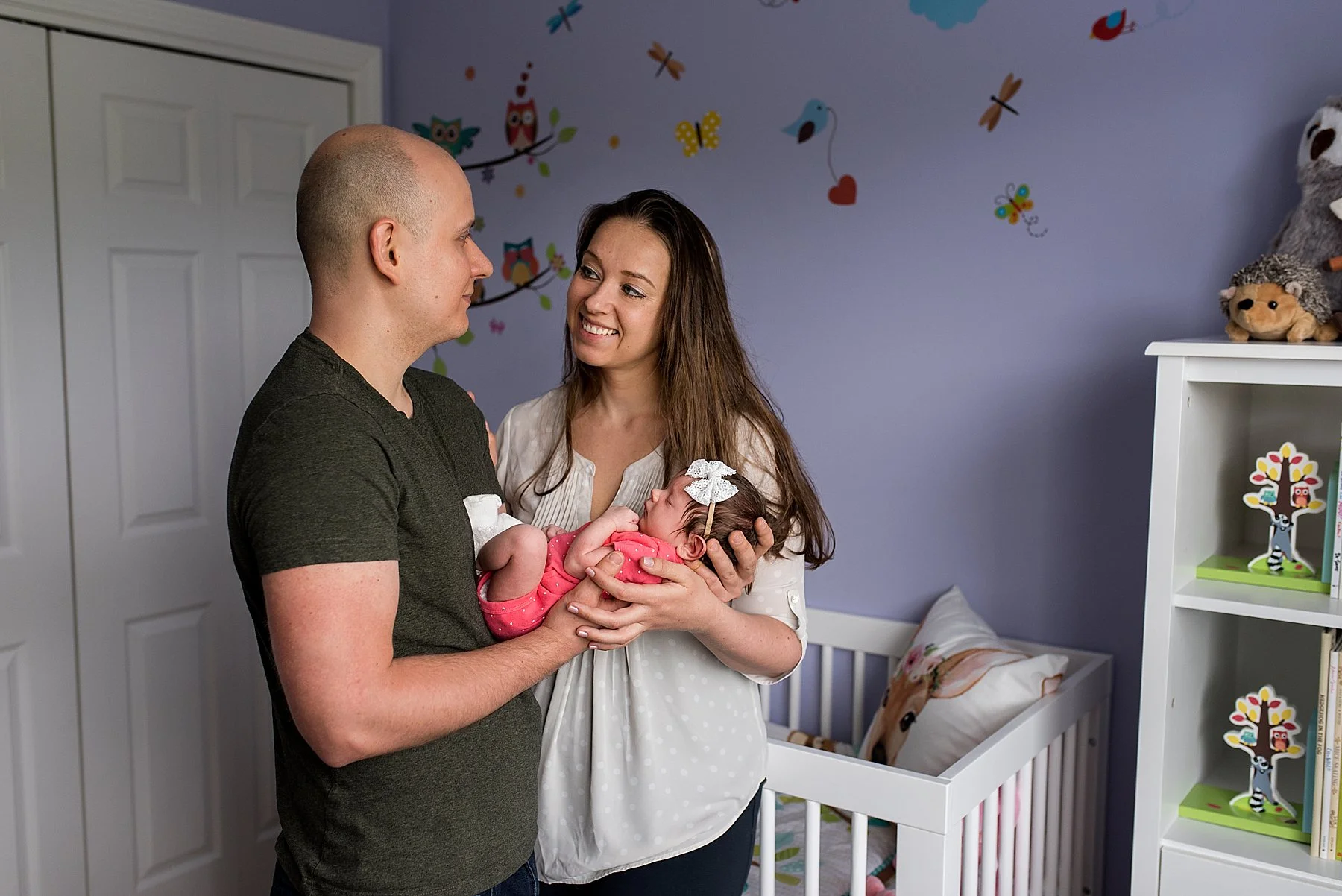 new parents holding newborn daughter in nursery during connecticut baby photography