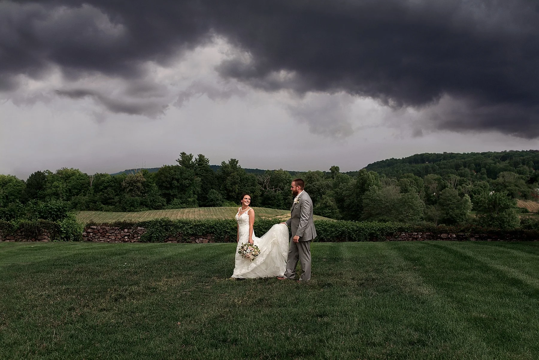 groom holding brides dress during storm on wedding day in CT