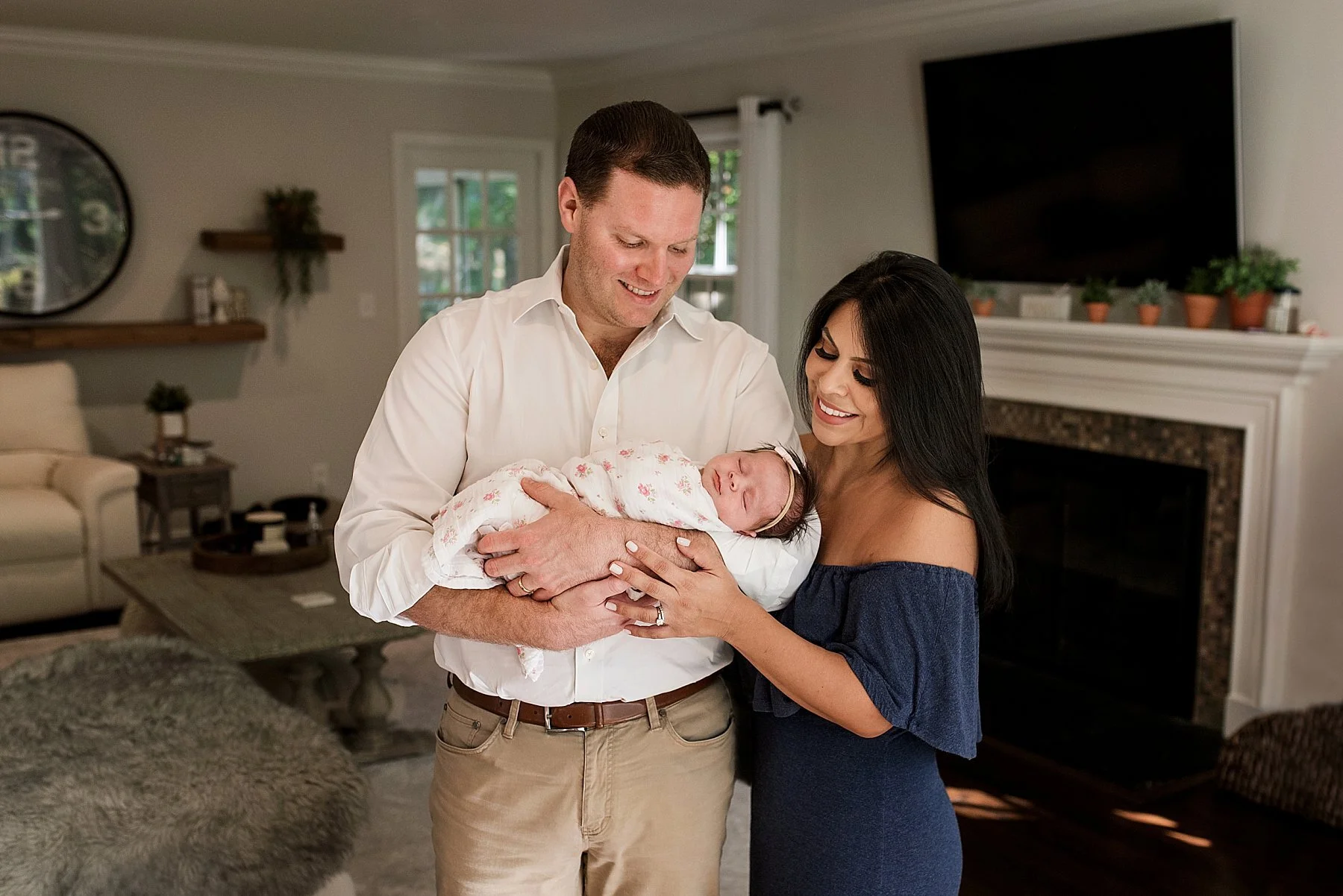 mom and dad holding newborn daughter curing baby photo session in fairfield county