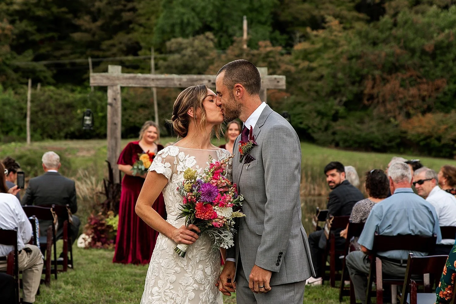 A bride and groom share a romantic kiss during their enchanting outdoor wedding ceremony, captured beautifully by a skilled CT wedding photographer.