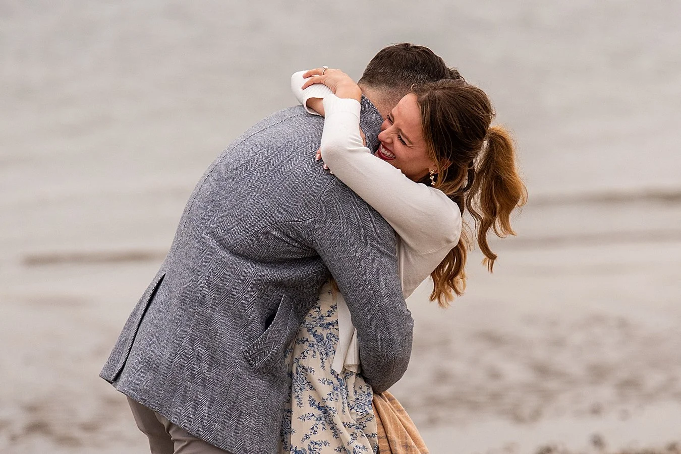A couple hugging on the Walnut Beach pier during a sunset engagement session.