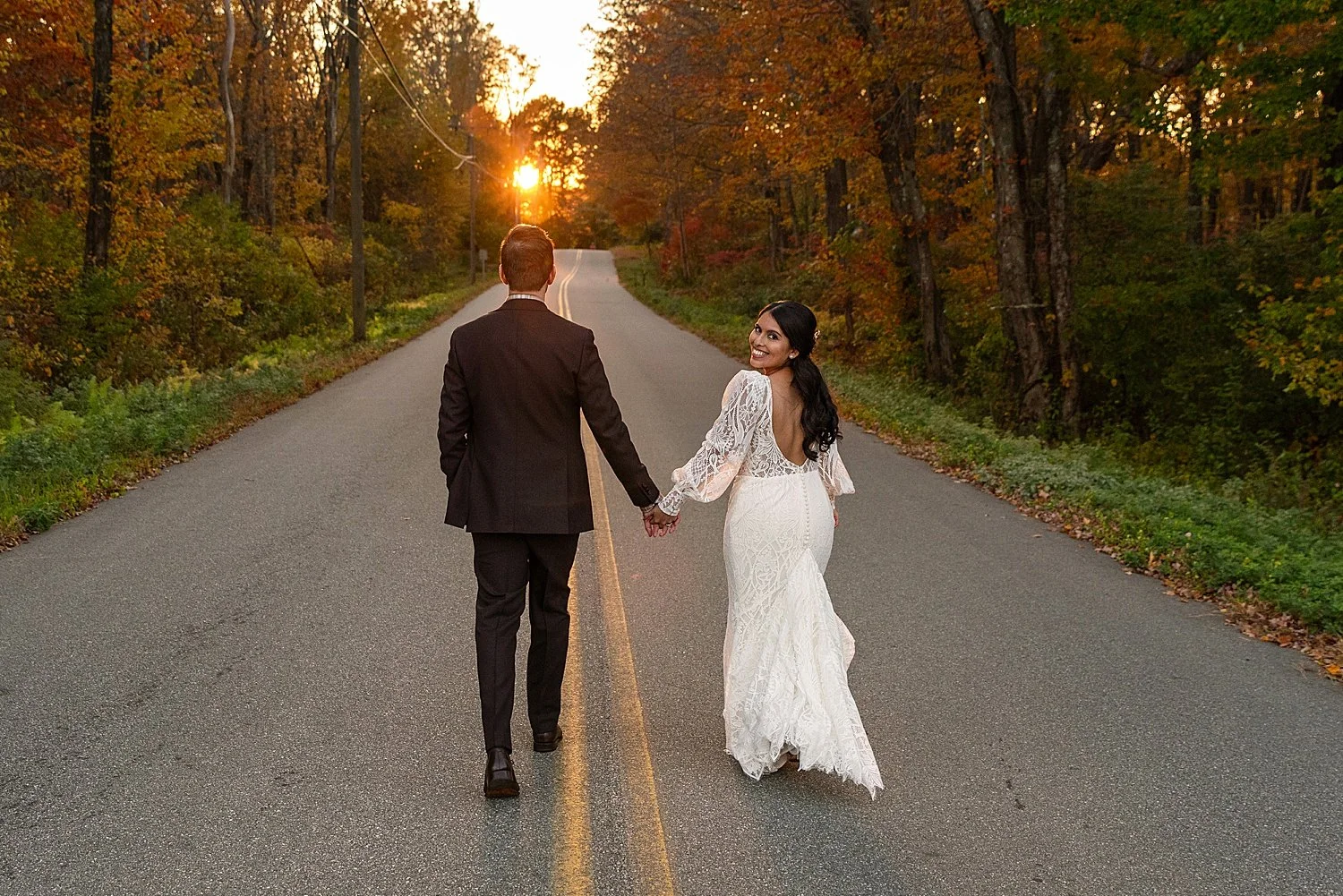 bride and groom hand in hand walking down the street as the sun sets