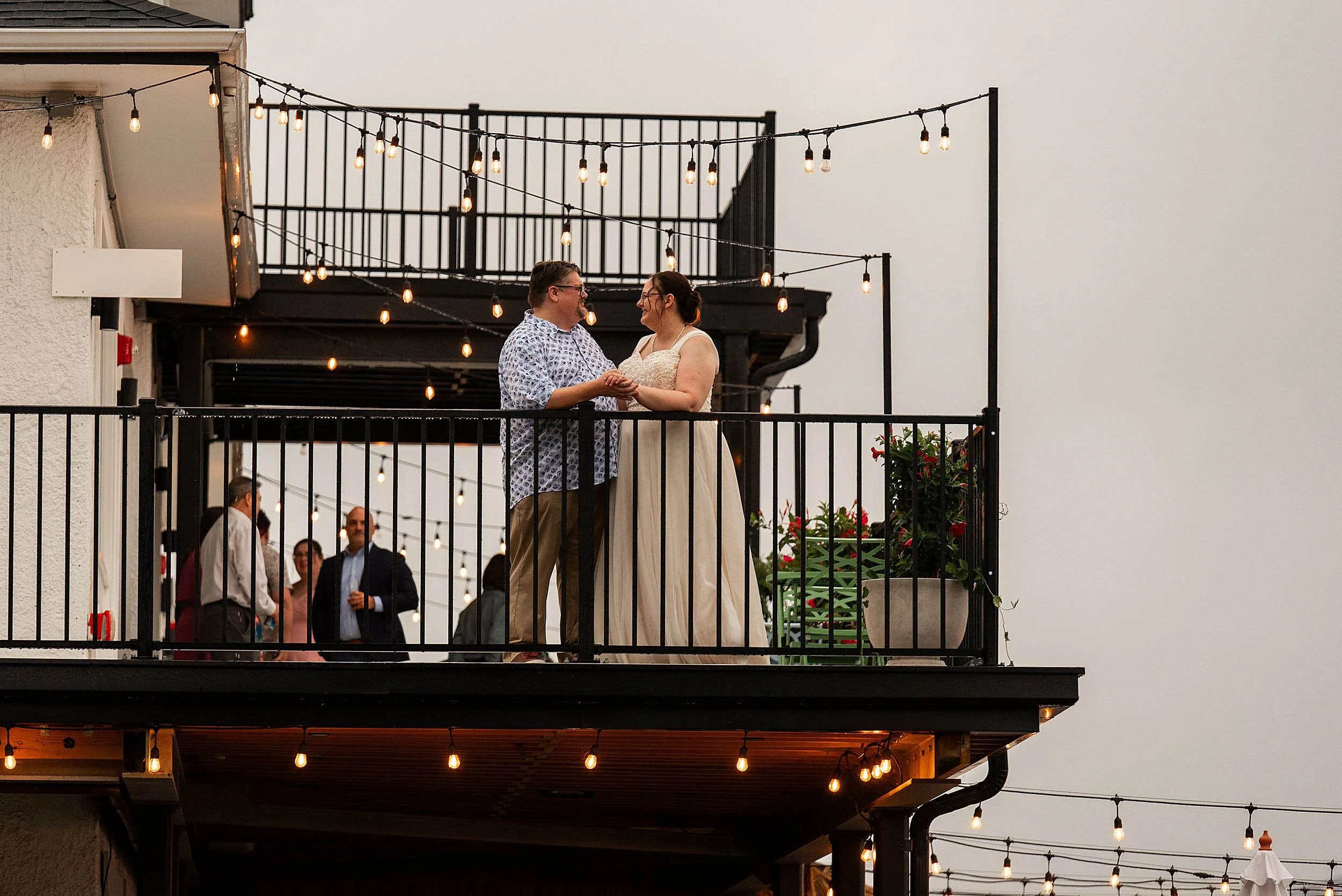 Wedding couple standing on balcony with bistro lights at Tates in Middletown CT