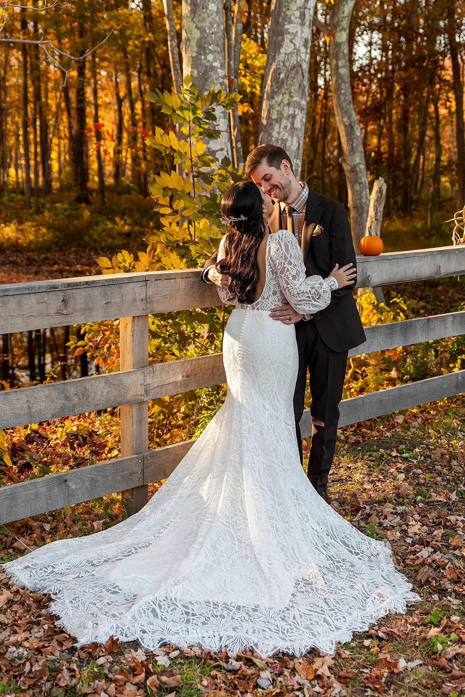 dramatic photo of wedding dress train as bride and groom embrace in the golden light of a Fall sunset in Connecticut