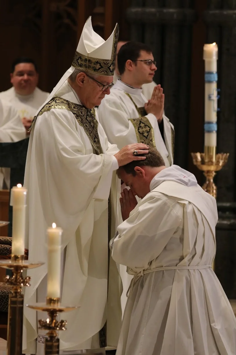 Bishop Tobin ordaining new priest.