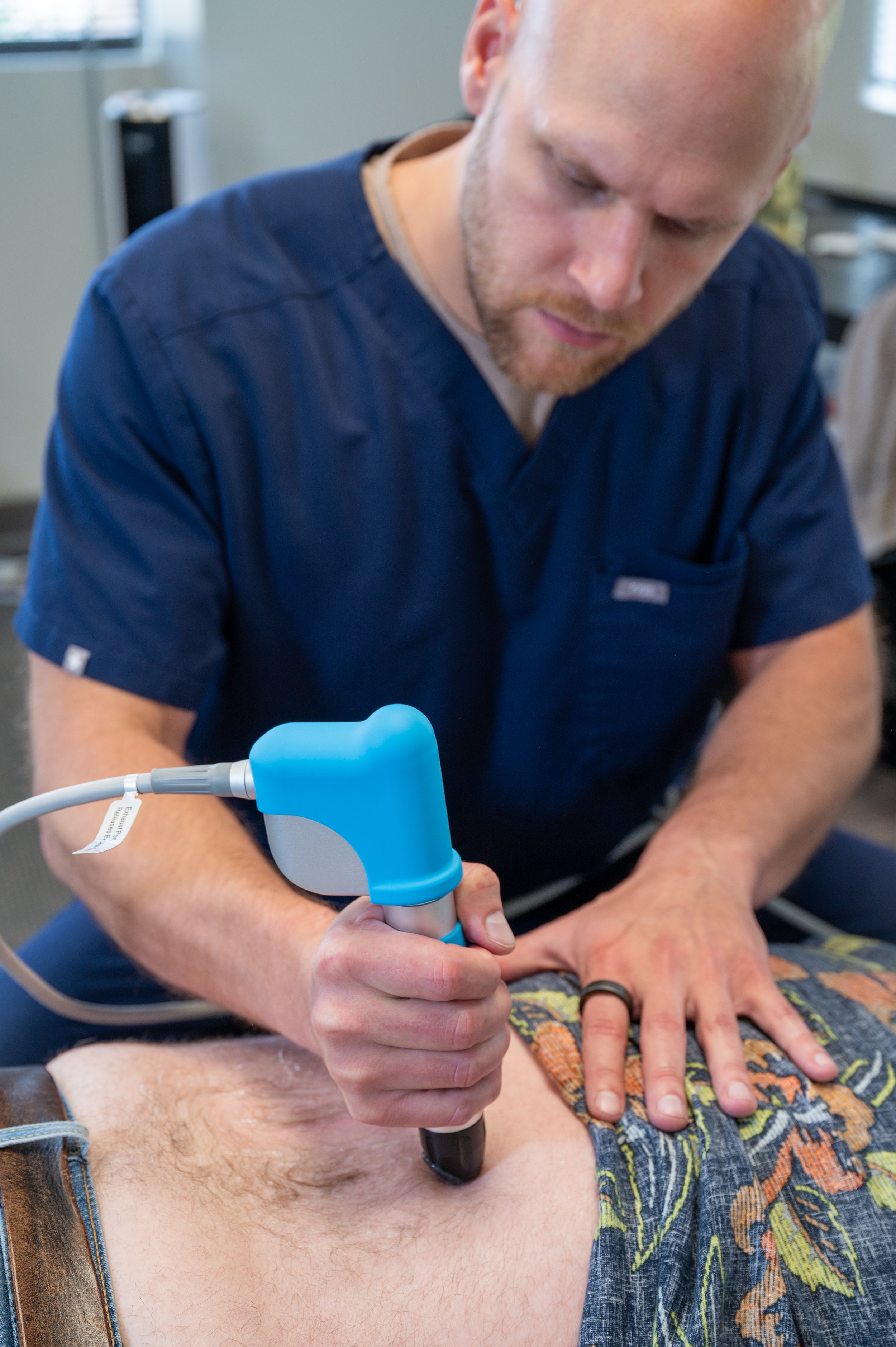 Medical professional performing a procedure on a patient's abdomen using shockwave therapy